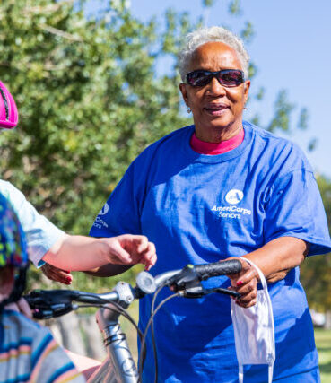 AmeriCorps Seniors volunteer smiling with children in bike helmets